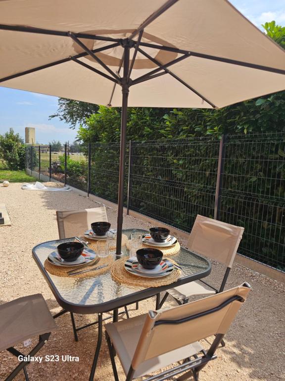 a glass table with chairs and an umbrella at La maison de villenouvelle in Toulouse