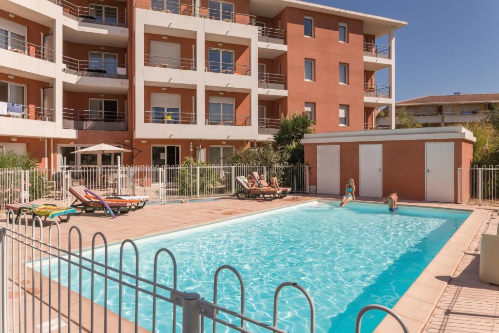 una piscina di fronte a un condominio di Appart'City Classic Aix-en-Provence - La Duranne ad Aix en Provence