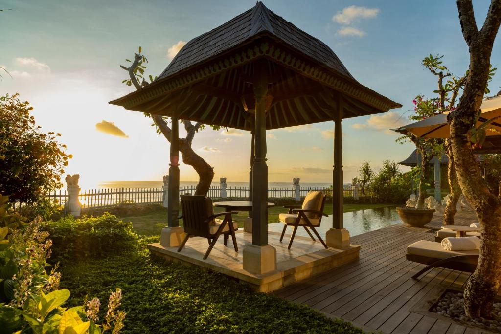 a wooden deck with a gazebo with chairs and an umbrella at Jumeirah Bali in Uluwatu
