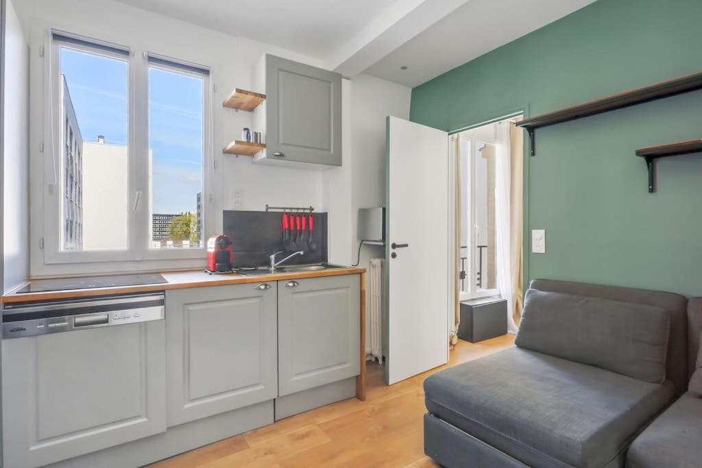 a kitchen with a sink and a couch in a room at 9-minute walk from La Défense - 1 bedroom in Courbevoie