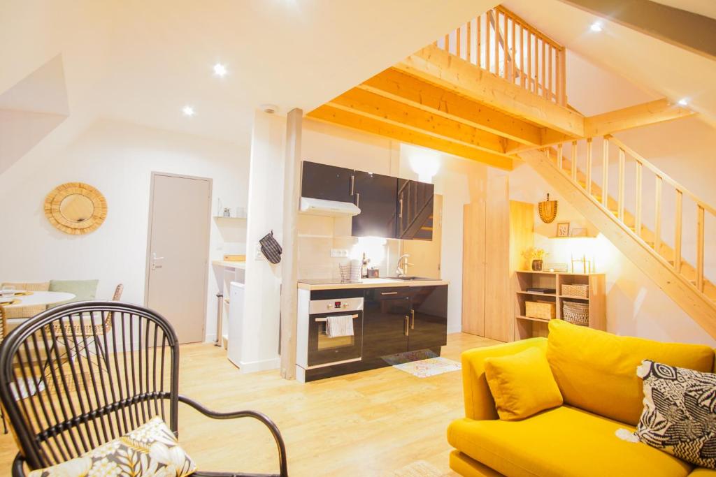 un salon avec un canapé jaune et une cuisine dans l'établissement -LE CHALET- Joli cocon au centre de Concarneau, à Concarneau