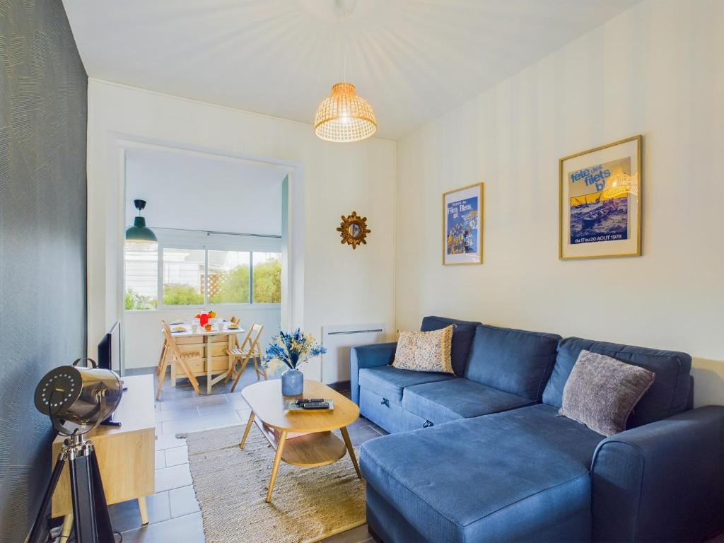 un salon avec un canapé bleu et une table dans l'établissement -ALYS- Charmant T2 proche plage, à Concarneau