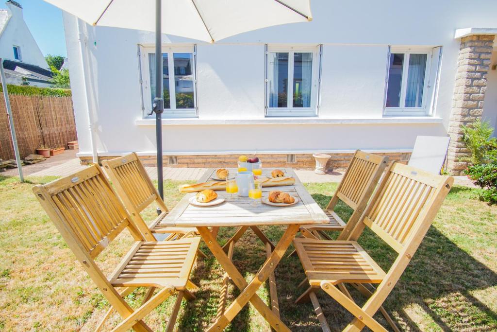 a table with chairs and an umbrella in a yard at -LE SENTIER- Elegant T3 avec jardin proche mer in Concarneau