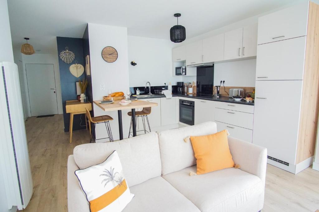 un salon avec un canapé blanc et une cuisine dans l'établissement -SHELBY- T2 Arriere corniche parking et terrasse, à Concarneau
