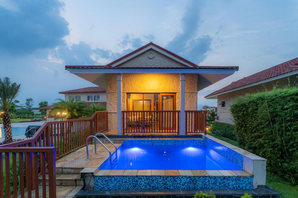 a house with a swimming pool in front of a house at River Bank Jungle Resort, Chitwan in Chitwan