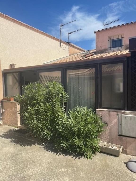 une maison avec des portes en verre et des plantes devant elle dans l'établissement Petite maison proche plage !, à Saint-Cyprien