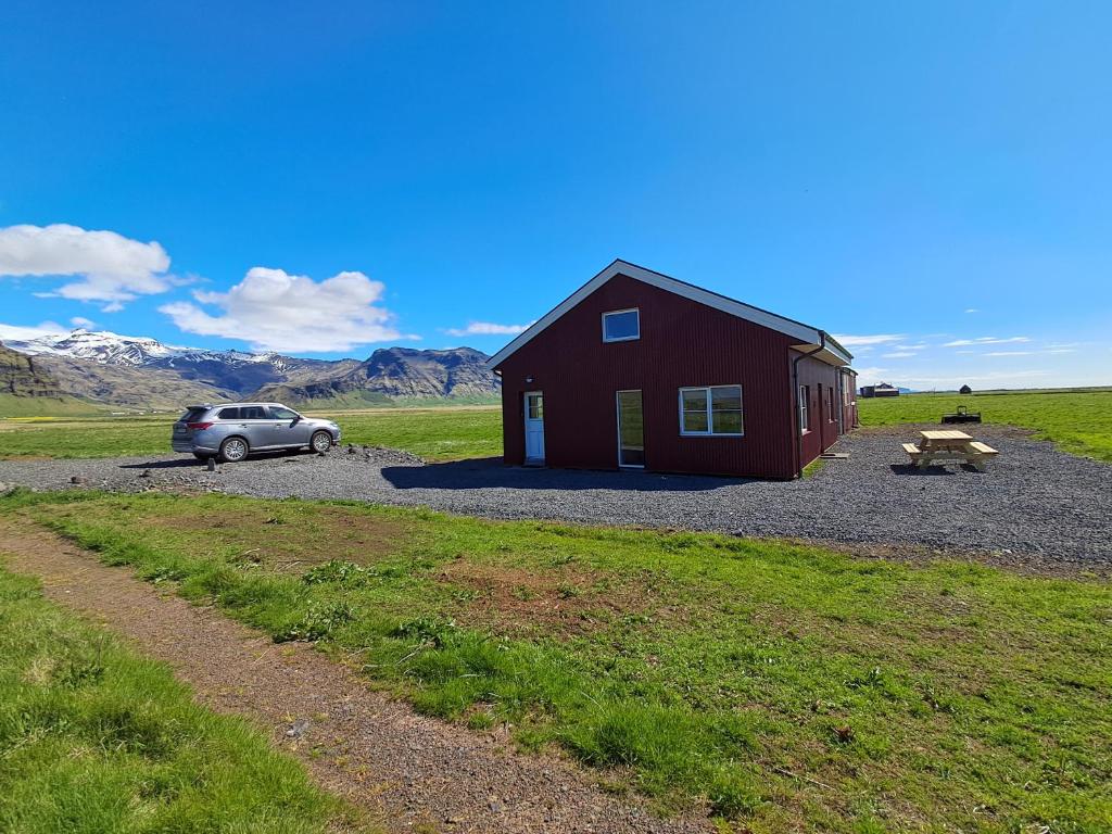 a red barn with a car parked next to it at The Forgotten Farmhouse in Skogar