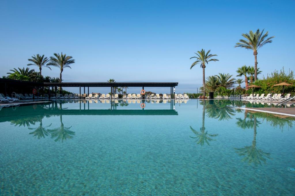 uma grande piscina com palmeiras e cadeiras em Impressive Playa Granada Golf em Motril