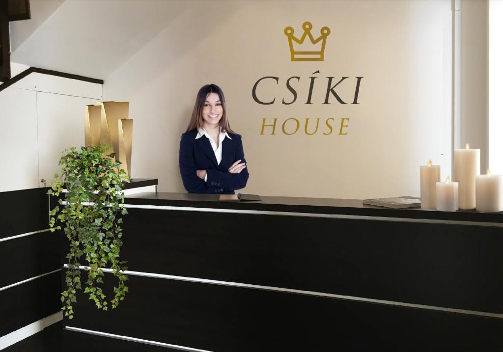 a woman standing at the reception desk of a csis house at Csiki Hotel in Miercurea-Ciuc