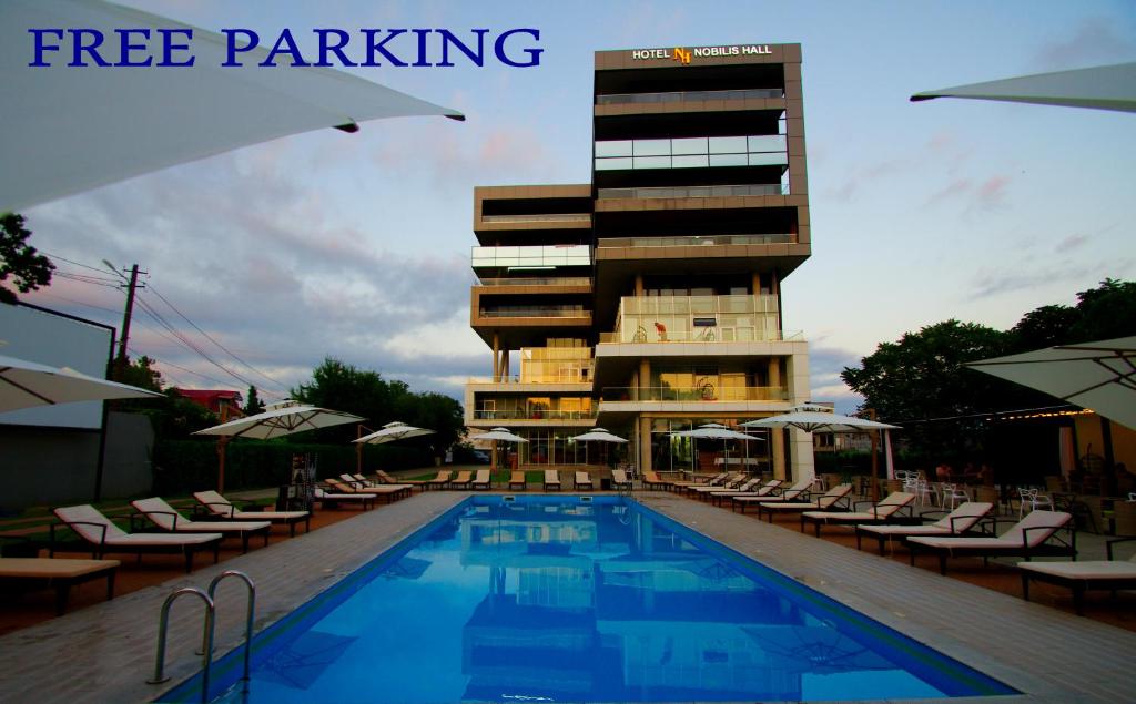 a hotel with a swimming pool in front of a building at Hotel Nobilis Hall in K'obulet'i