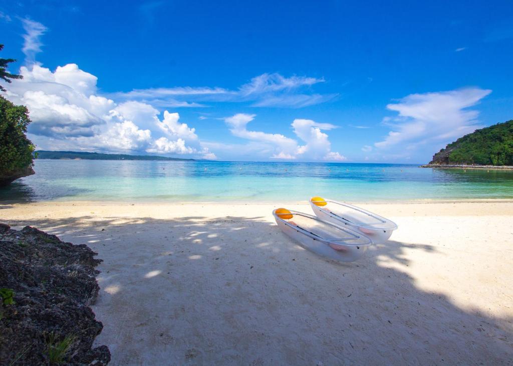 two boats sitting on a sandy beach next to the ocean at Fairways and Bluewater Boracay in Boracay