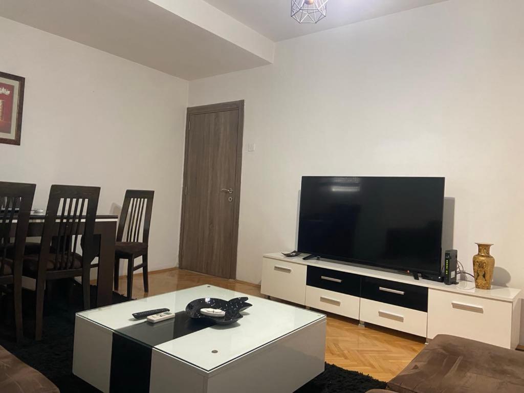 a living room with a flat screen tv and a table at Centar Apartment in Kumanovo