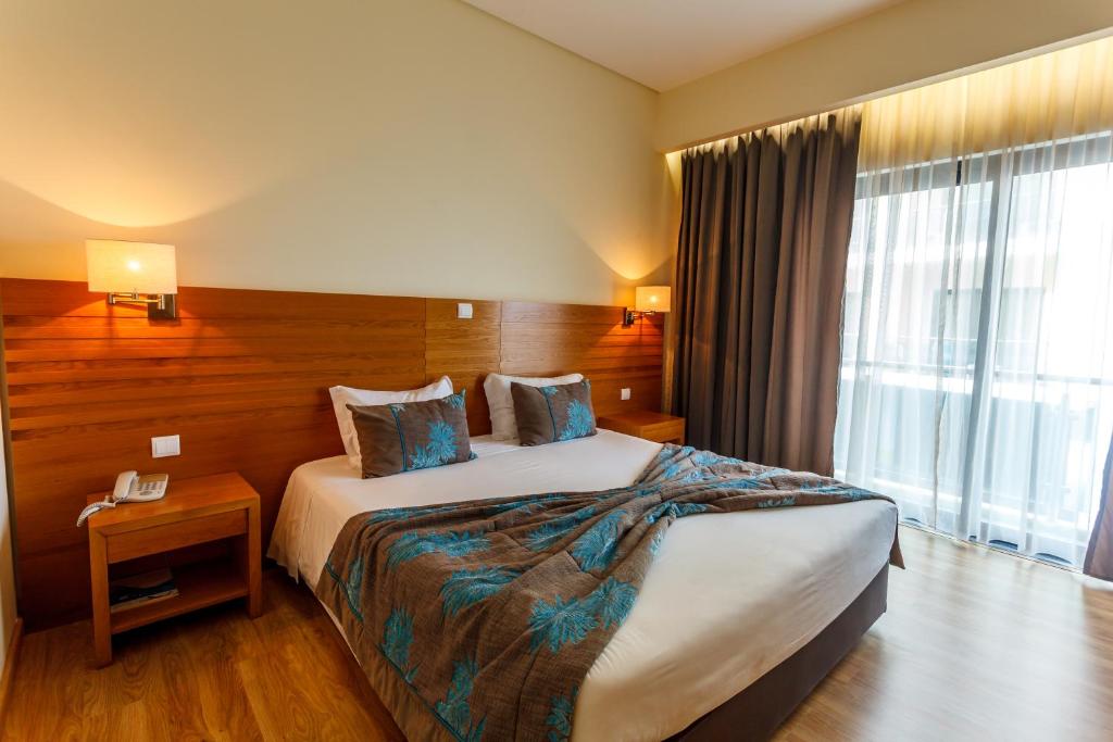 a hotel room with a bed and a large window at Hotel Caravelas in Madalena