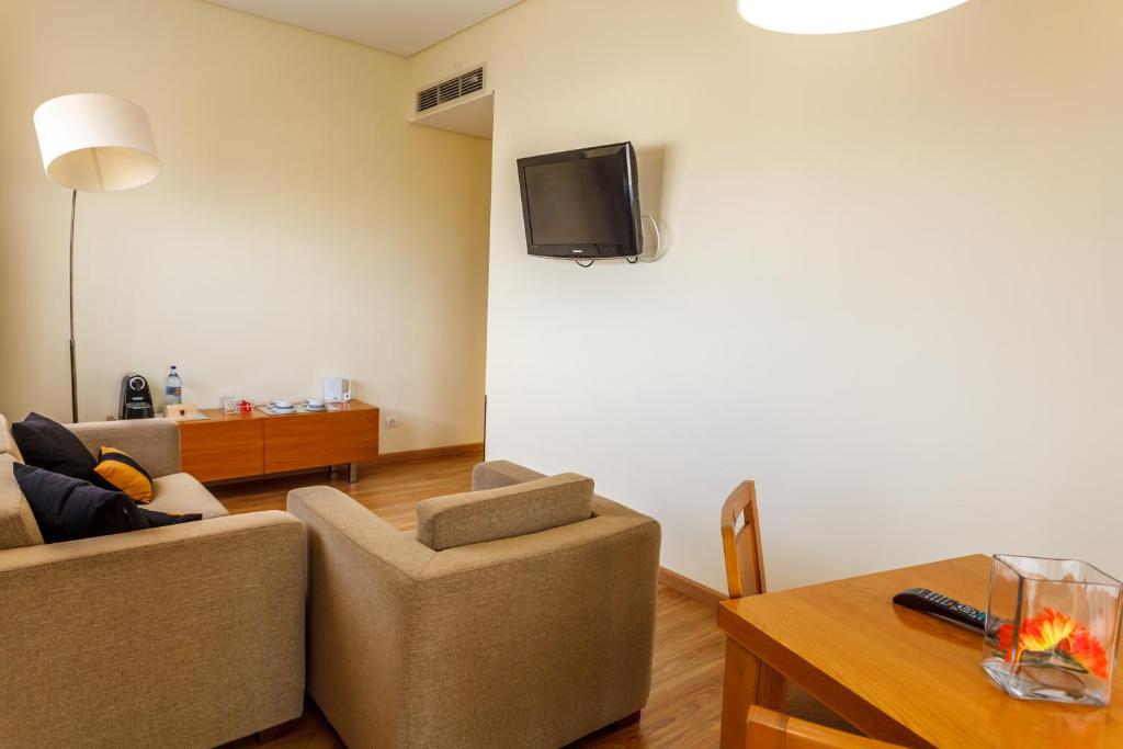 a living room with a couch and a tv on a wall at Hotel Caravelas in Madalena