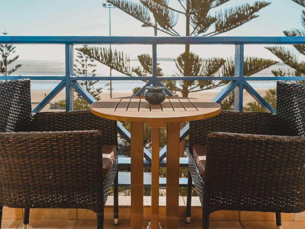 a table with two chairs and a table with a vase on it at Le Médina Essaouira Thalassa Sea & Spa - MGallery Collection in Essaouira