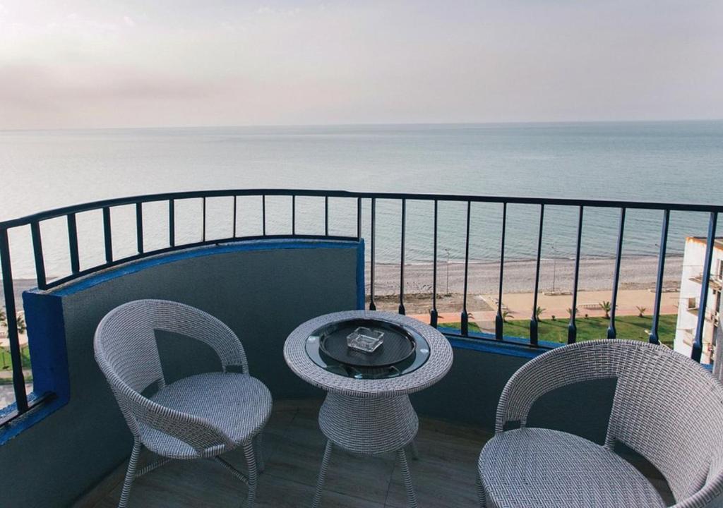 een balkon met 2 stoelen en een tafel en de oceaan bij Horizon Batumi Aparthotel in Batoemi
