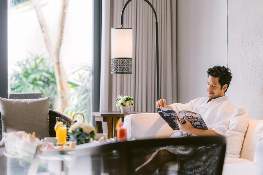 a man sitting on a couch reading a book at Jumeirah Bali in Uluwatu