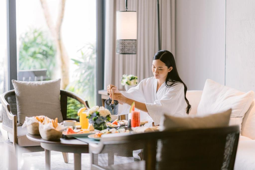 a woman sitting at a table eating food at Jumeirah Bali in Uluwatu
