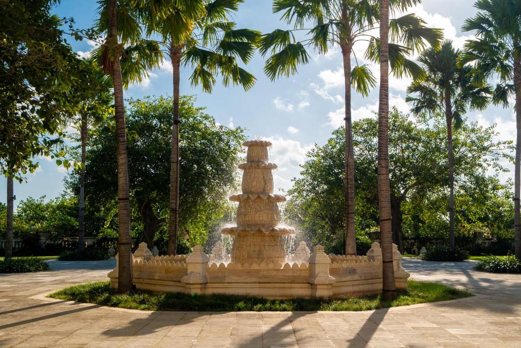 a fountain in the middle of a park with palm trees at Jumeirah Bali in Uluwatu