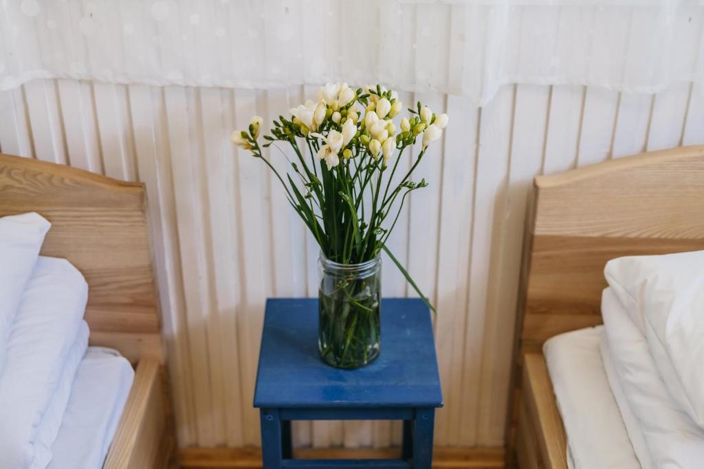 a vase of flowers on a blue table between two beds at Guboja in Nida