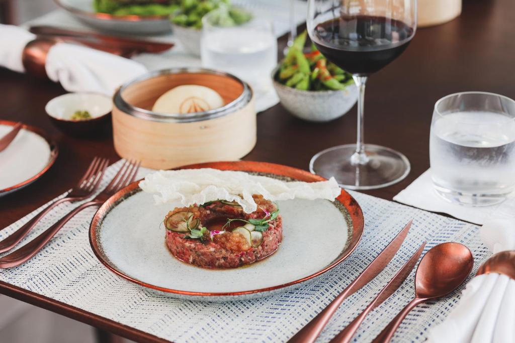 a table with a plate of food and a glass of wine at Jumeirah Bali in Uluwatu