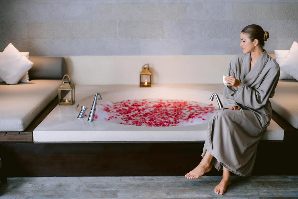 a woman sitting in a bath tub with a red substance at Jumeirah Bali in Uluwatu