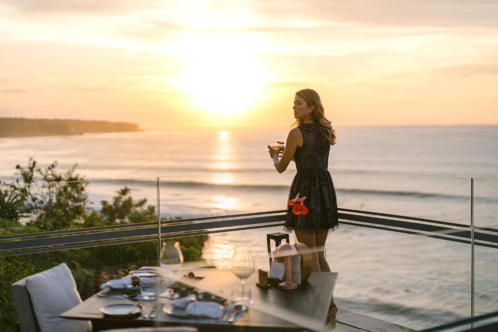 a woman standing on a balcony looking at her cell phone at Jumeirah Bali in Uluwatu