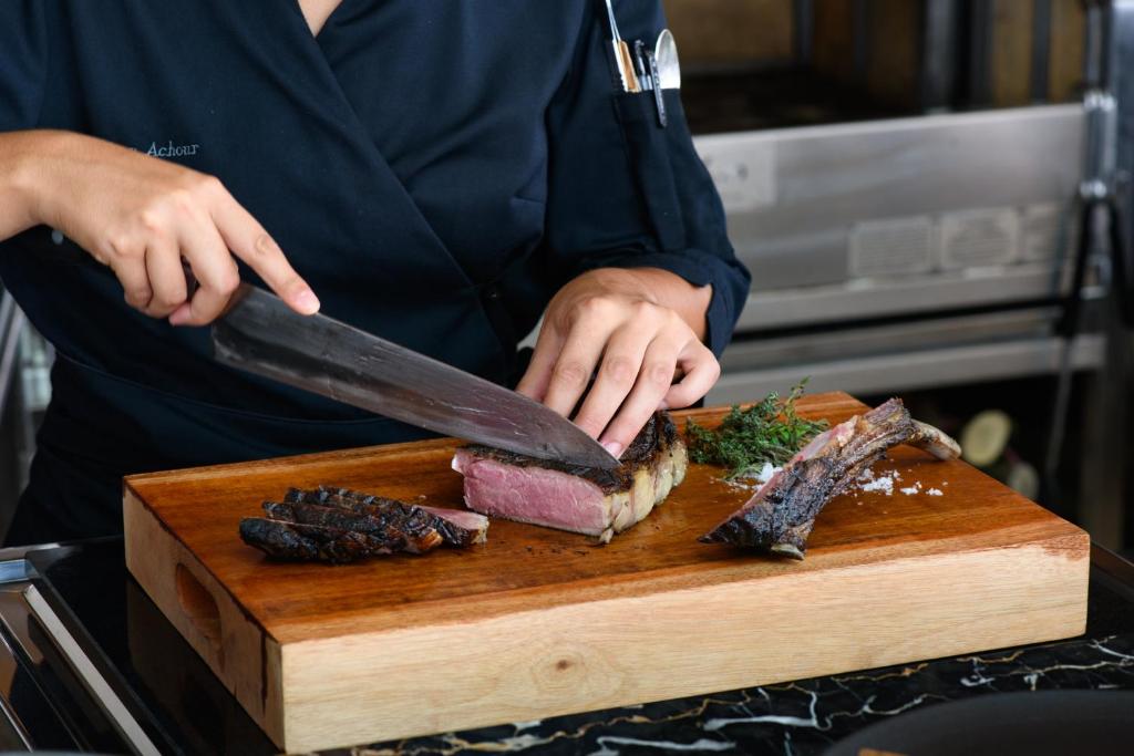 a person cutting a piece of meat on a cutting board at Jumeirah Bali in Uluwatu