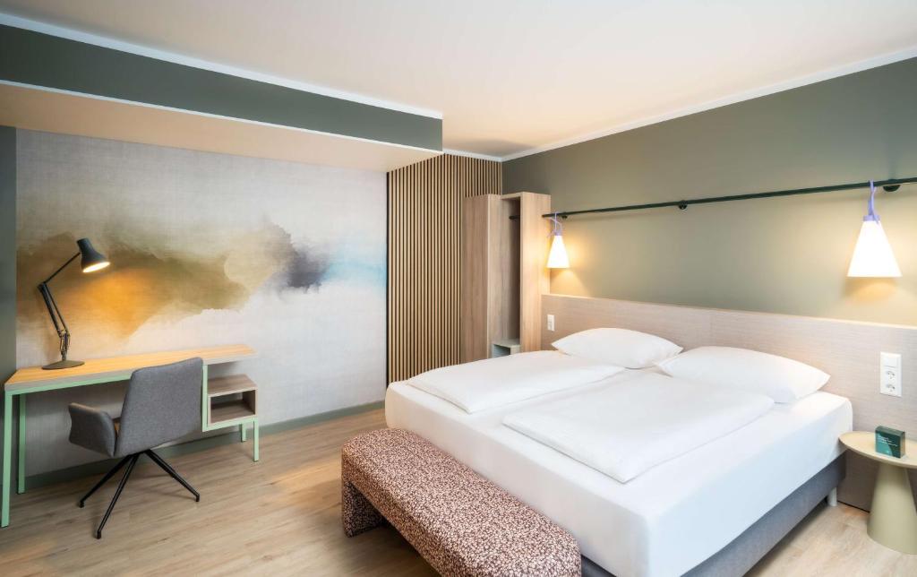a bedroom with a white bed and a desk at elaya hotel stuttgart ludwigsburg ehemals Abacco by Rilano in Korntal-Münchingen