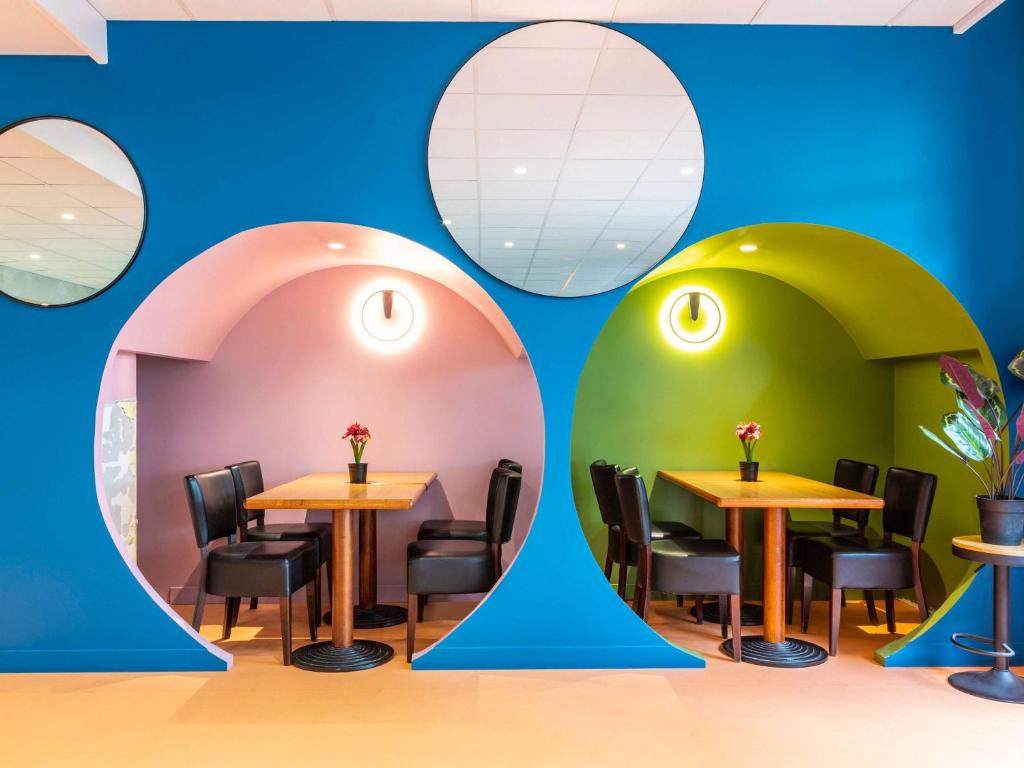 un restaurante con mesas y sillas y una pared con círculos en ibis Styles Paris Saint Denis Pleyel, en Saint-Denis