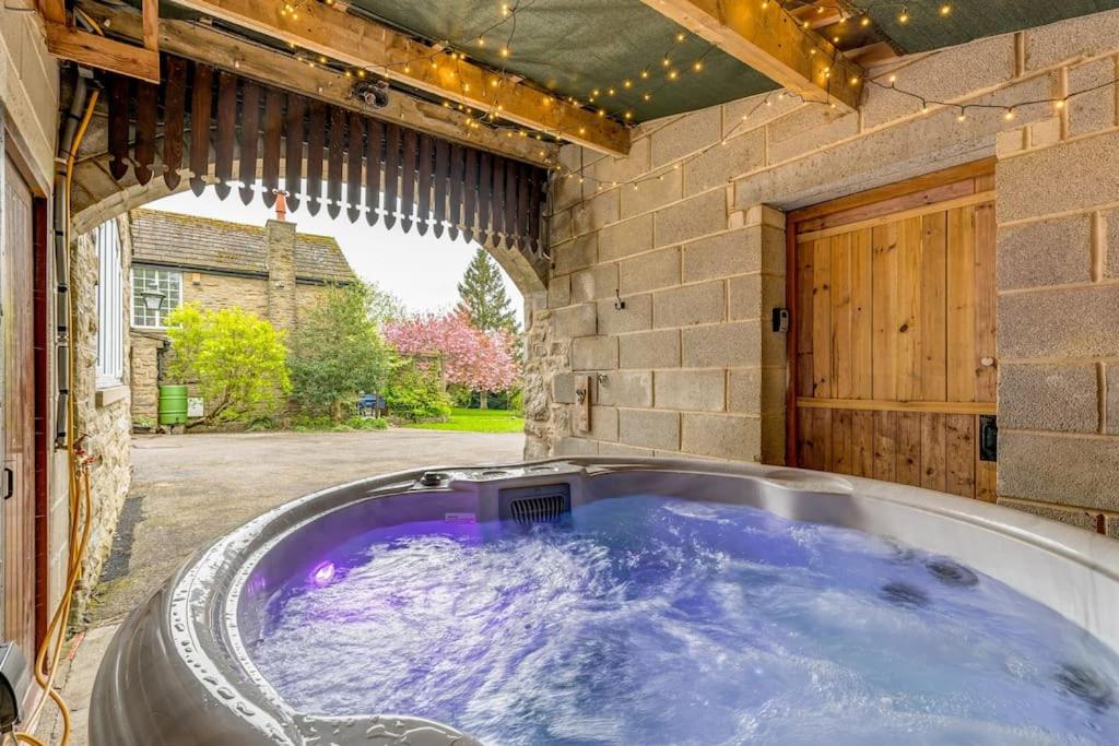 une baignoire jacuzzi dans une arrière-cour avec une porte dans l'établissement Malham Wellbeing 1-bed Retreat With Hot Tub, à Malham