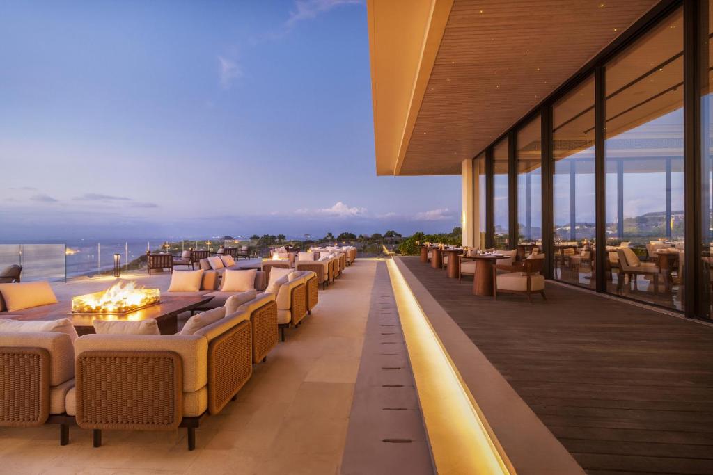 a restaurant with tables and chairs on a balcony at Jumeirah Bali in Uluwatu