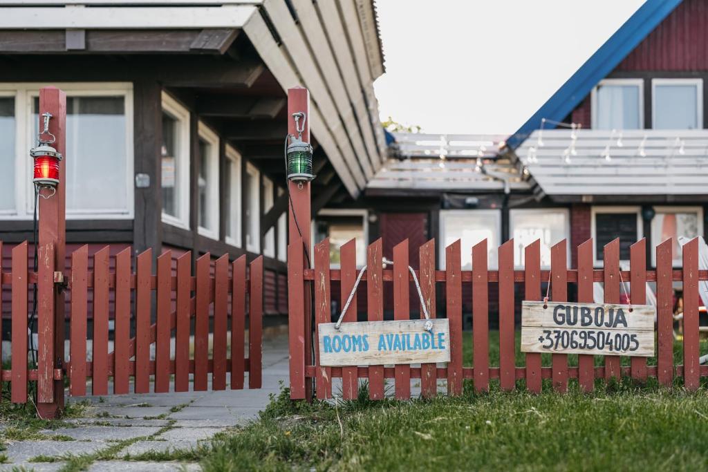 a red fence in front of a house with a sign at Guboja in Nida