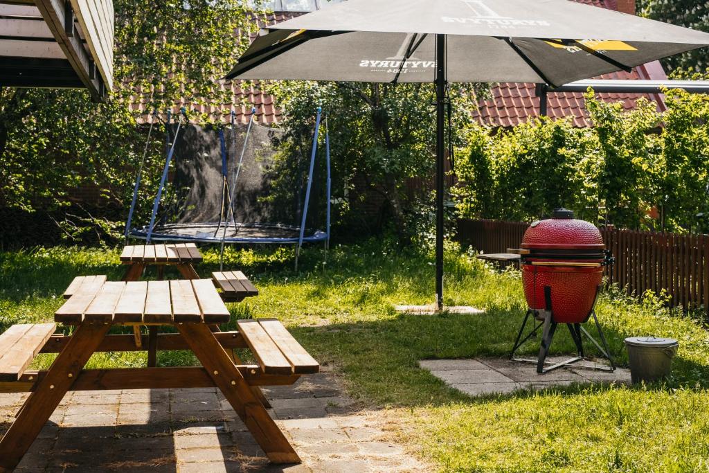 a picnic table and a grill with an umbrella at Guboja in Nida