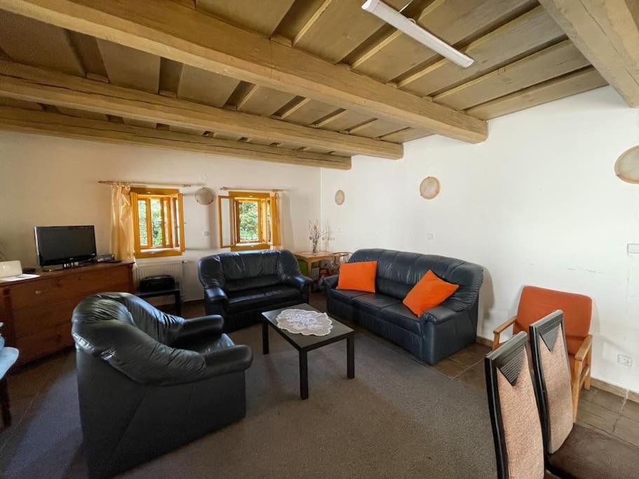 una sala de estar con muebles de cuero negro y almohadas de color naranja. en Chata EVA v krásnej dedinke, en Závadka nad Hronom