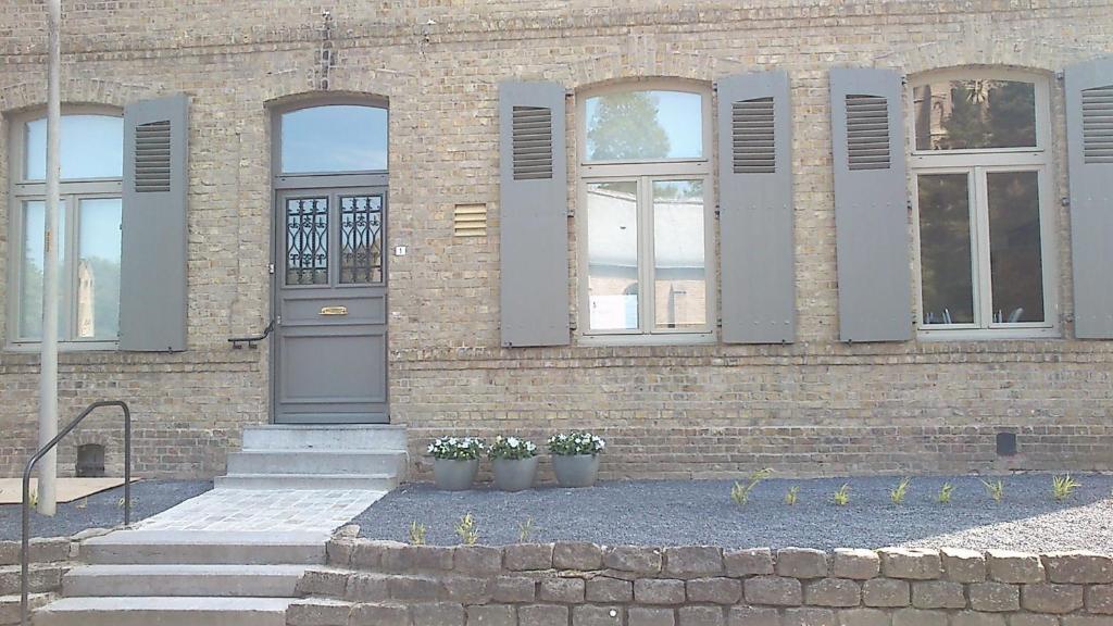 um edifício de tijolos com dois vasos de plantas em frente em De Pastorie - Zillebeke em Ieper