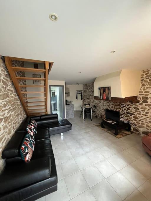 un salon avec un canapé en cuir noir et une cheminée dans l'établissement Maisonnette charmante 4 personnes proche de Vannes, à Grand-Champ