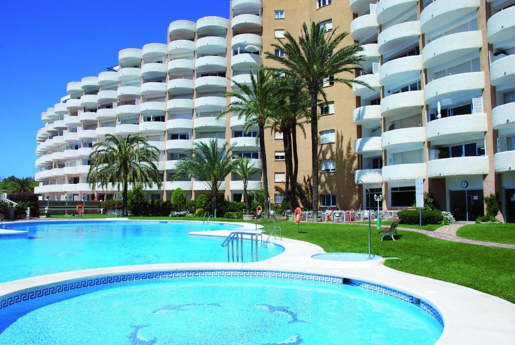 a swimming pool in front of a large apartment building at Apartamentos Coronado in Marbella