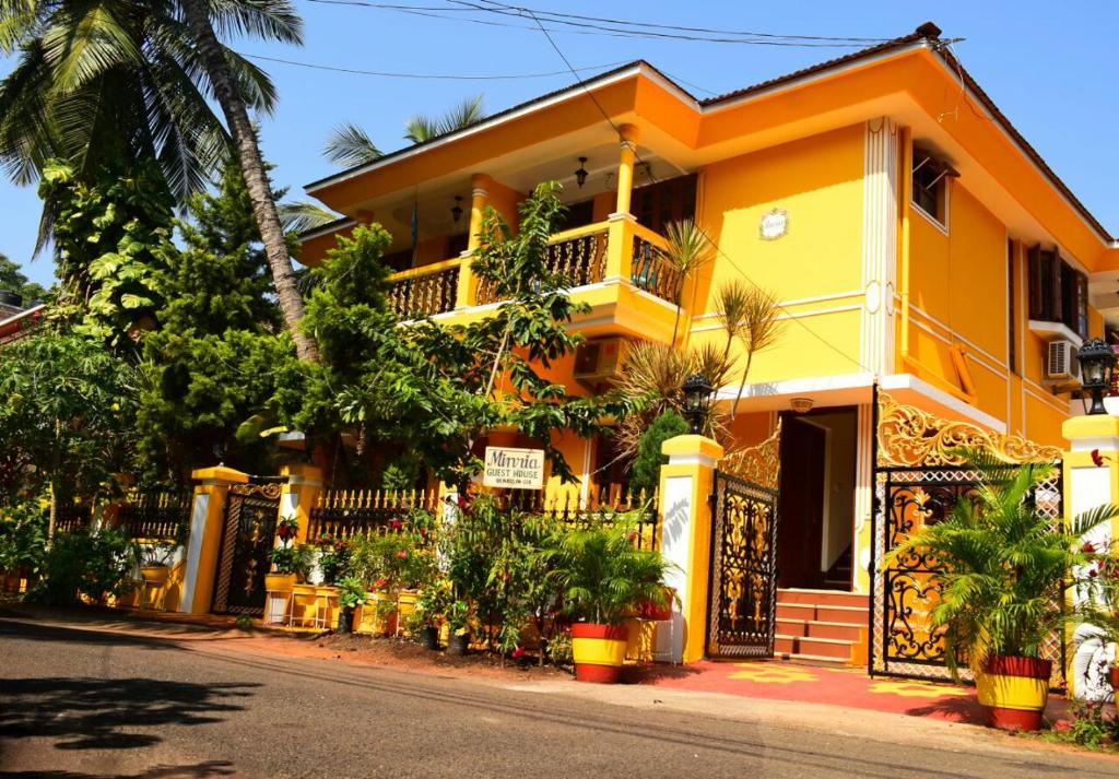 a yellow building with a gate and a street at Minria Guest House in Benaulim