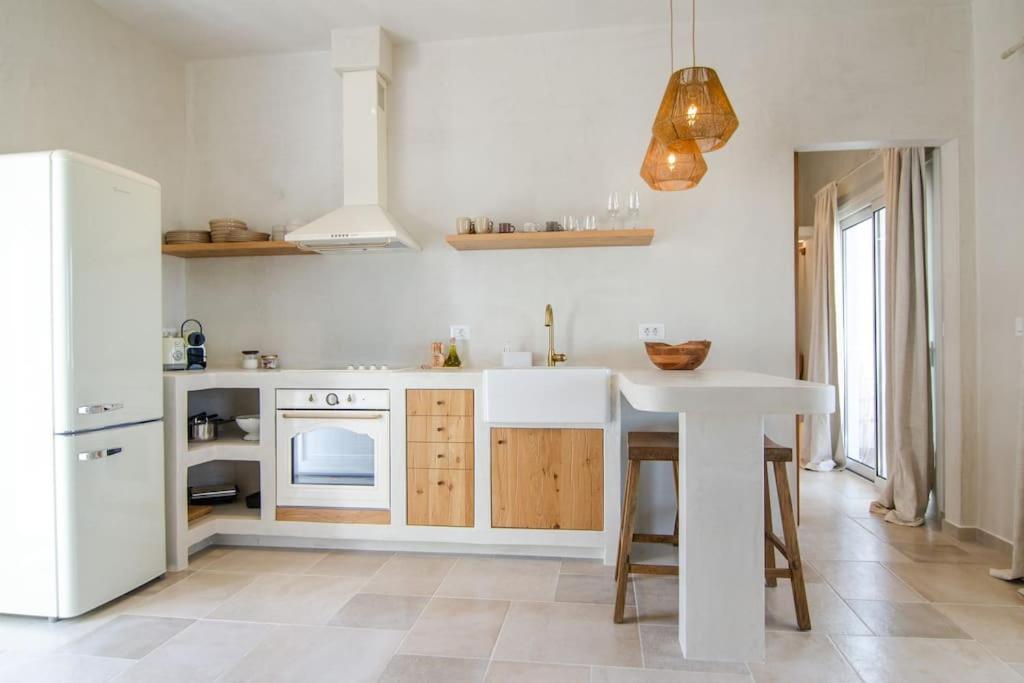 a kitchen with a white refrigerator and a table at Sea sound in Mylopotas