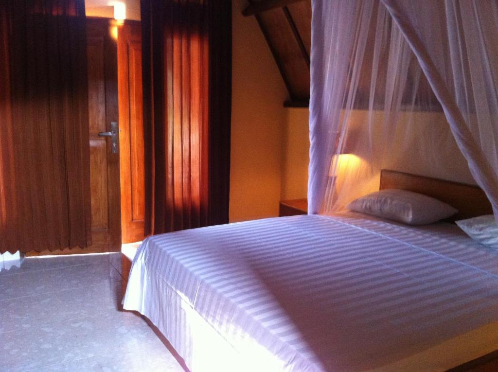 a bedroom with a white bed with a canopy at Dinoyin Bungalows in Gili Meno