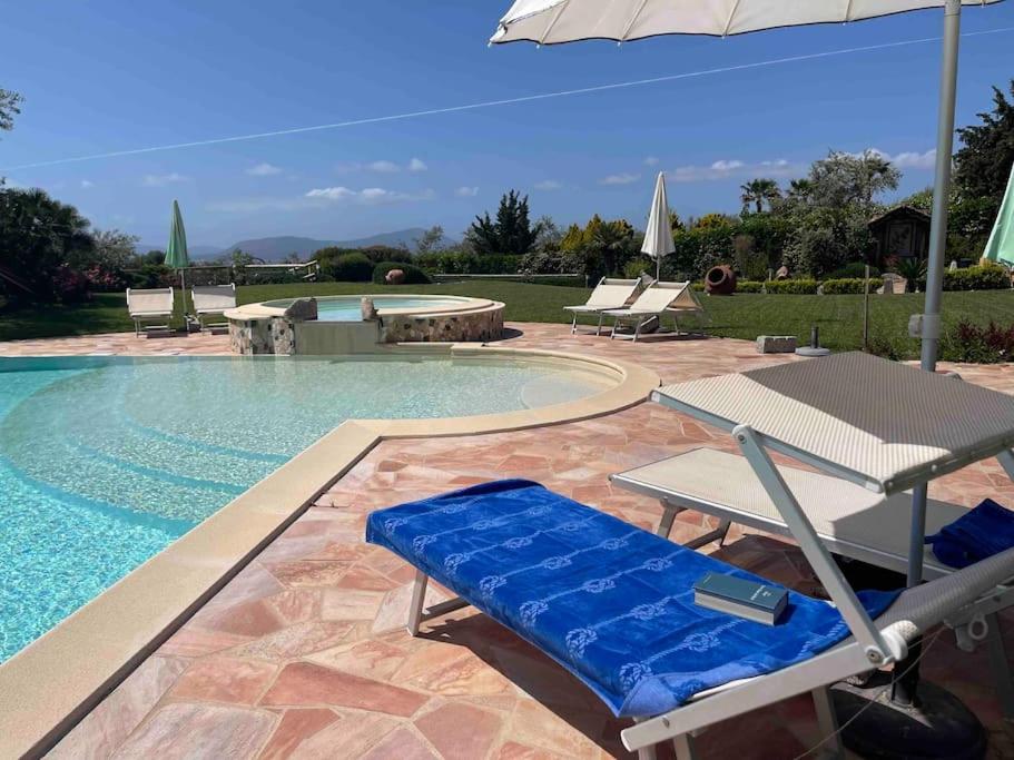 a pool with chairs and a table and an umbrella at Appartamento Burantinu in Alghero