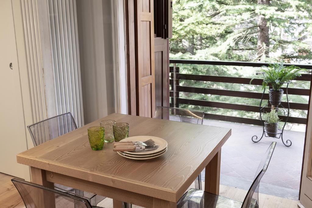 Una mesa de madera con platos y vasos encima en una habitación. en Bijoux Sozzine, en Ponte di Legno
