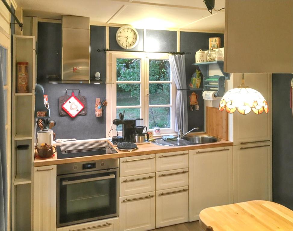 a kitchen with white cabinets and a clock on the wall at Bungalow de 2 chambres avec piscine privee jardin clos et wifi a Saint Chamassy a 3 km de la plage in Saint-Chamassy