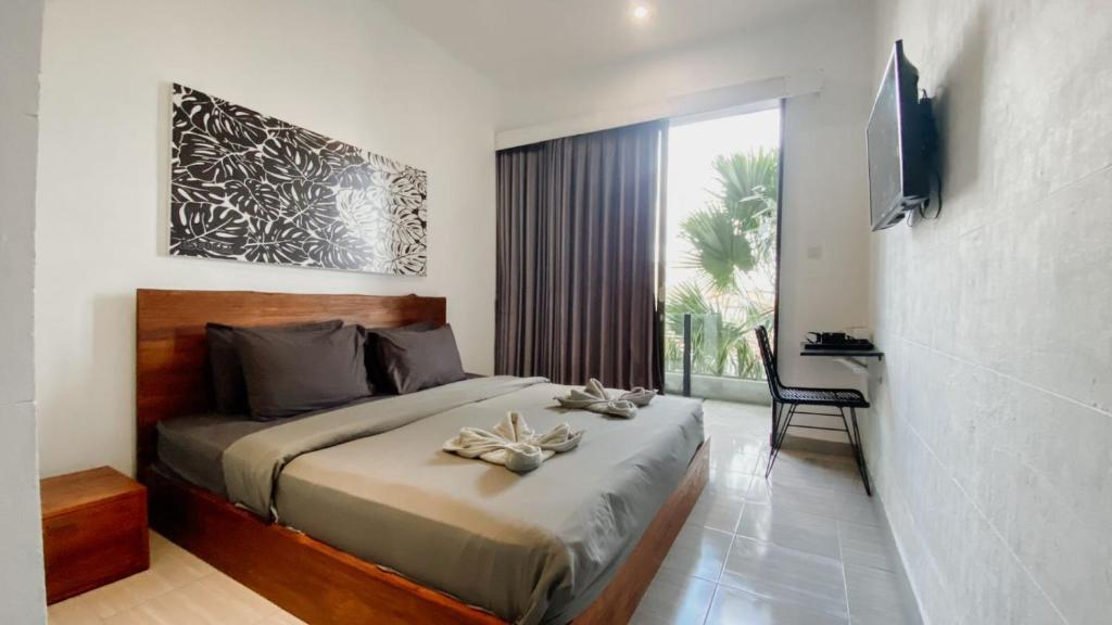 een slaapkamer met een bed, een bureau en een televisie bij Escotel Vanili Guest House in Canggu