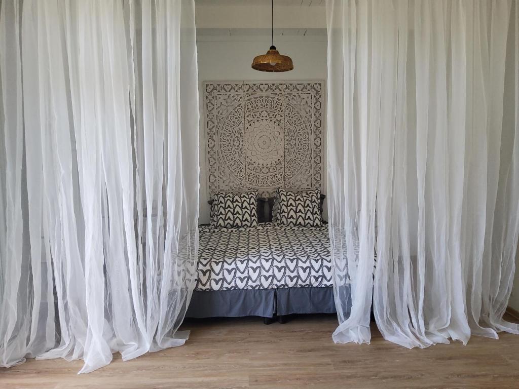 a bed with white curtains in a room at LE RUBINJO Case fleurie in Saint-Benoît