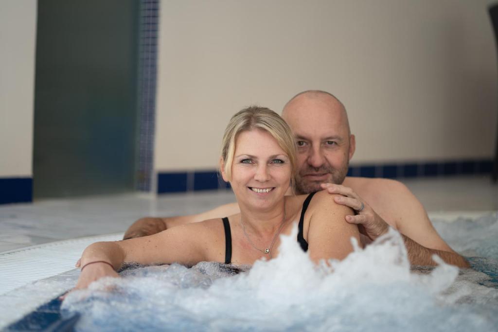 um homem e uma mulher numa banheira de hidromassagem em Spa & Wellness Hotel Olympia Marienbad em Mariánské Lázně
