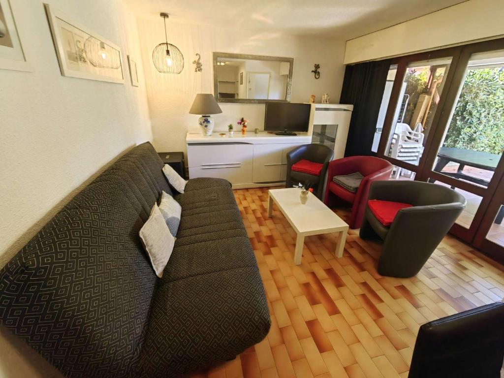 - un salon avec un canapé noir et des chaises dans l'établissement Superbe T3 avec piscine, tennis, parking près de la plage pour 6 pers, terrasse au RDC - FR-1-607-2, au Cap d'Agde