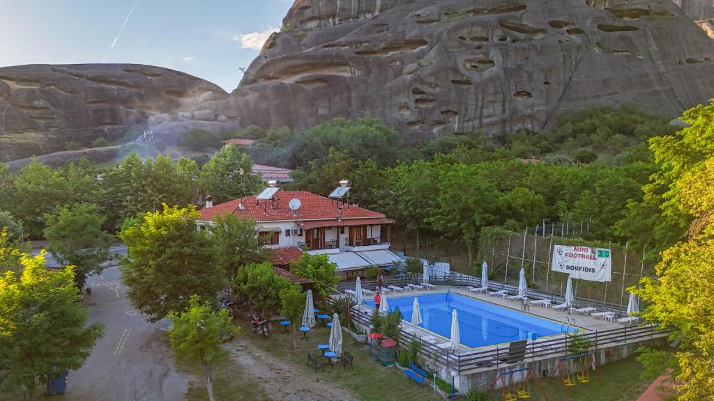 a house with a swimming pool in front of a mountain at Boufidis Rooms in Kalabaka