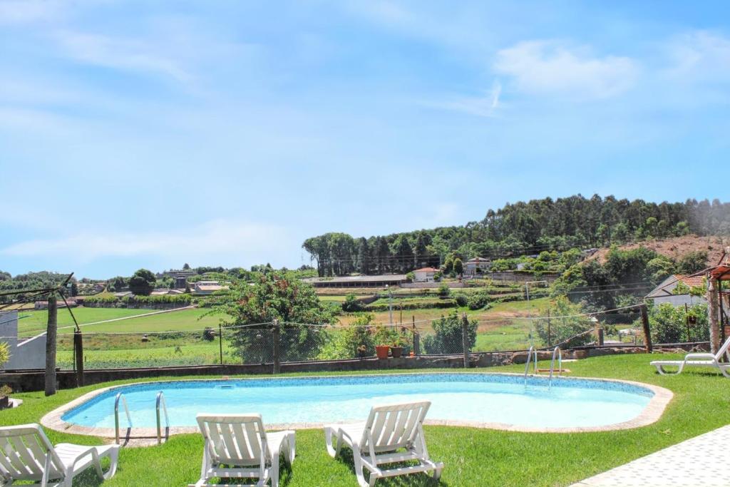 uma piscina com duas cadeiras de relva na relva em 2 bedrooms house with shared pool enclosed garden and wifi at Requiao em Requião